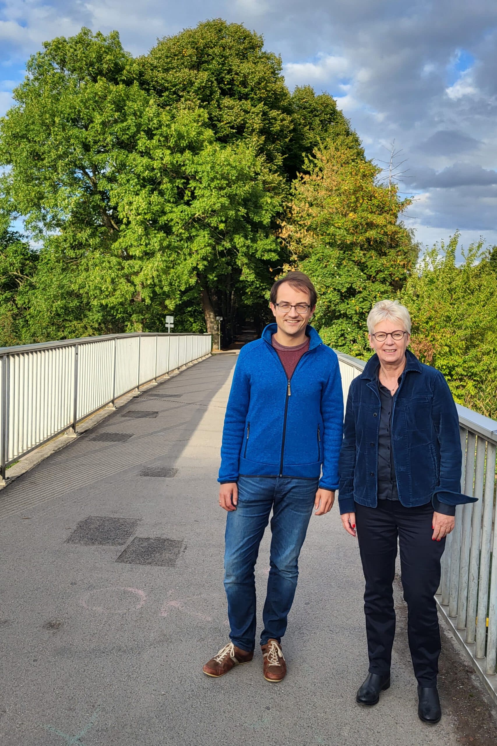 Bundestagsabgeordneten Maria Klein-Schmeink und Landtagsabgeordneten Robin Korte stehen auf einer Brücke über einen Kanal